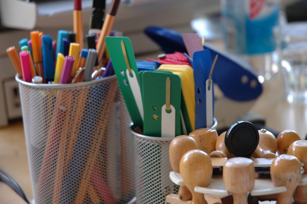 Ein Symbolbild, welches Büroutensilien darstellt. Sowohl Stifte, als auch Stempel. Sie stehen Stellvertretend für die Bürokratie im Prozess.